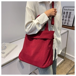 Detail of red corduroy shoulder bag showing texture and adjustable strap on model