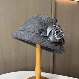 Detailansicht der dunkelgrauen Wollglocke mit Seidenrose und Netzschleier am Hutständer