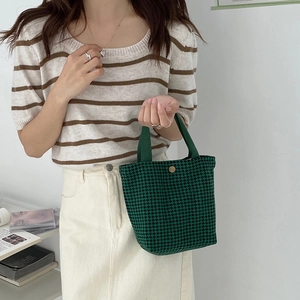 Detail of green houndstooth wool tote bag with dark nylon handles and gold snap button