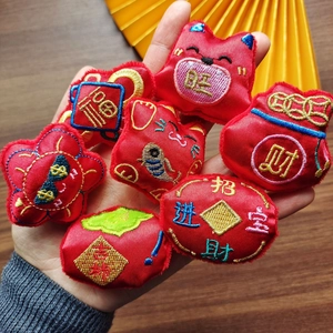 Hand holding set of 7 red embroidered Chinese New Year lucky charms with gold characters