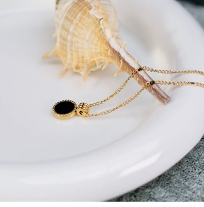 Detail of 18K gold plated necklace with black round pendant and elegant bead edge trim