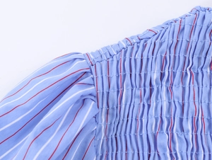 Détail du smockage et des rayures sur le tissu alvéolé d'un chemisier bleu clair