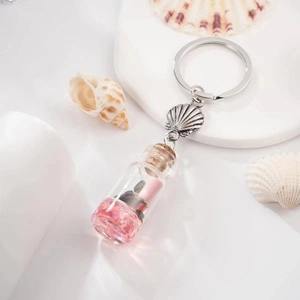 Close-up of a seashell drift bottle keychain with pink crystals and silver hardware