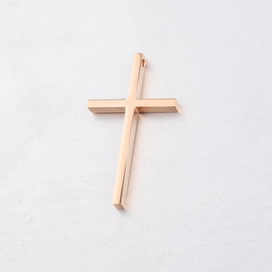 Macro shot of rose gold stainless steel cross pendant with polished mirror finish