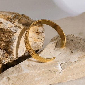Primer plano detallado de la superficie con textura martillada dorada en el brazalete en C