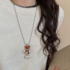 Detail of a brown flocked bear necklace with white pearls on a silver-tone chain