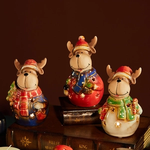 Three ceramic reindeer Christmas figurines with glowing star cutouts on vintage books