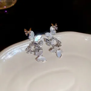 Elegant butterfly tassel earrings with zircons and mother-of-pearl on a ceramic tray