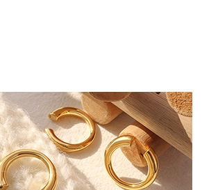 Detailed view of minimalist gold hoop earrings on wooden stand with soft lighting
