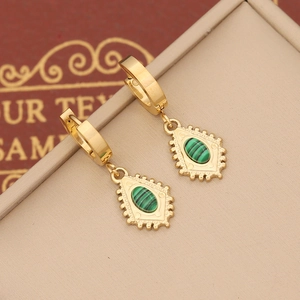 Detail of vintage gold earrings with green stone inlay on a beige jewelry box