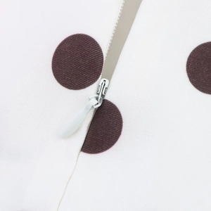 Détail de la fermeture éclair métallique sur une robe blanche à pois avec texture du tissu