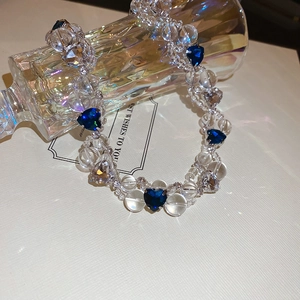 Detail of beaded necklace with blue heart crystal and transparent beads on white background