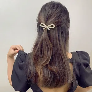 Elegant bow hair clip with sparkling rhinestones and pearls worn by model on hair