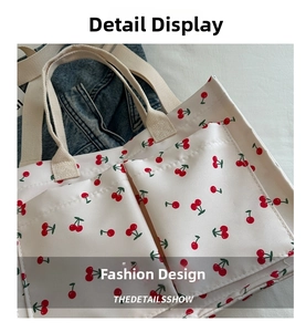 Close-up of white canvas tote bag with red cherry prints and two large front pockets