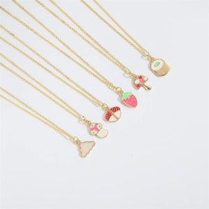 Close-up of enamel mushroom and strawberry pendant necklaces on gold chains