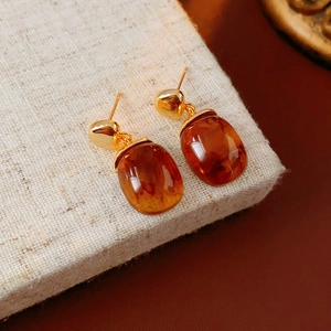 Close-up of vintage 18K gold plated resin stud earrings with amber oval stones on linen