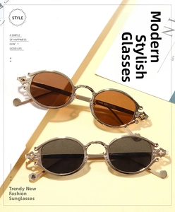 Close-up of vintage oval sunglasses with engraved gold metal frames and textured temples