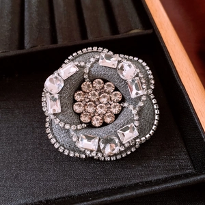 Close-up of a camellia flower brooch with grey tweed fabric and sparkling crystals