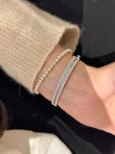 Gros plan d'un bracelet en perles et d'un jonc en argent serti de zircons
