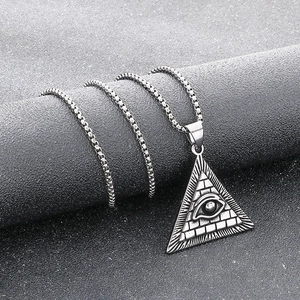 Macro shot of silver Eye of Providence pyramid pendant on a textured grey column display