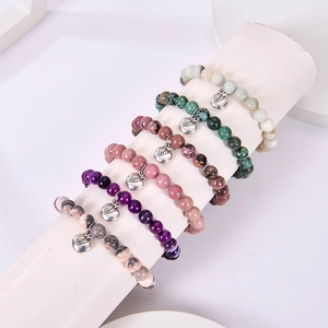 Stack of colorful beaded natural stone bracelets with silver apple charm pendants