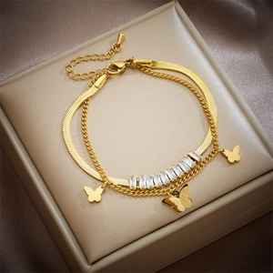 Detail of golden double-layer chain bracelet with butterfly charms and white zircons