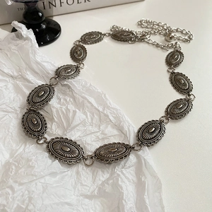 Detail of vintage silver metal waist chain with oval carved links on white background