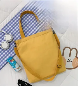 Detail of yellow canvas tote bag with adjustable shoulder strap and handheld handle