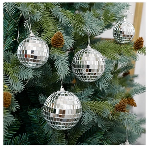 Gros plan de boules disco argentées de 30cm suspendues sur un sapin avec des pommes de pin