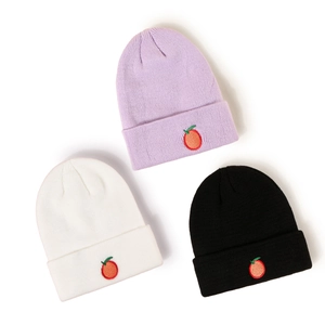 Trois bonnets tricotés pour enfants en violet, blanc et noir avec broderie orange