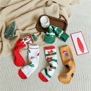 Detail of Christmas coral fleece socks with reindeer and tree patterns on soft rug