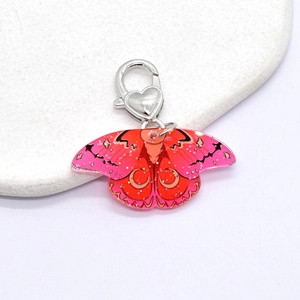 Detail of pink gradient acrylic butterfly keychain with silver heart clasp and glitter finish