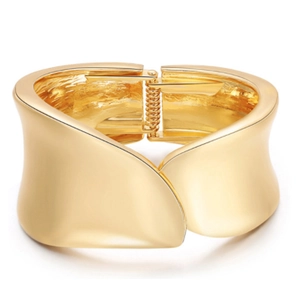 Close-up of golden wide cuff bracelet with wavy edges and polished mirror finish