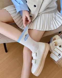 Detail showing white crew socks with pink bow patterns and blue cloud cartoon motifs