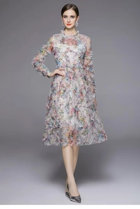 Detalle de vestido de gasa floral con manga larga, volantes escalonados y textura de malla