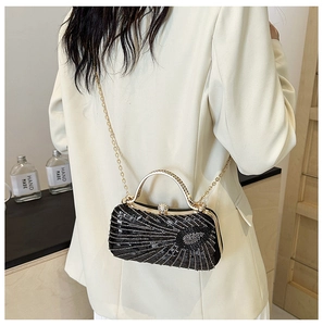 Fashionable black sequin evening bag with gold handle shown on a model's shoulder