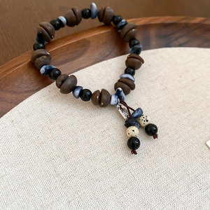 Close-up of vintage acrylic coffee bean beads and metal tag on a handmade bracelet