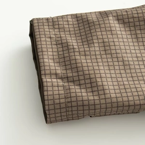Macro view of brown checkered pattern fabric and precision stitching on the jacket sleeve