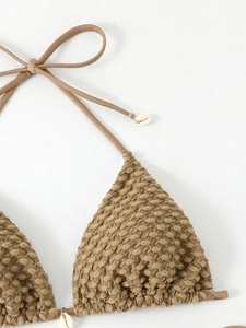 Detail of tan textured bikini top featuring shell accents on the adjustable ties