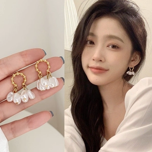 Detailed close-up and model wearing elegant gold hoop earrings with Baroque pearls