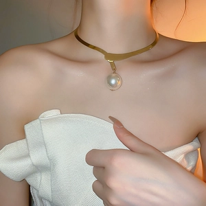 Close-up of elegant gold irregular collar necklace with large white pearl pendant on model