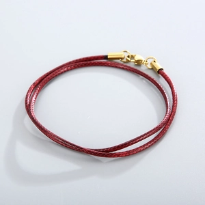 Detail of red braided wax cord necklace with a polished gold stainless steel clasp
