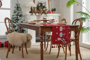 Detailed view of red Christmas table runner with festive jacquard patterns and tassels
