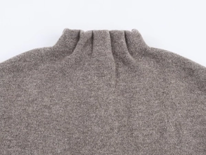 Macro shot showing high-neck ribbed knit texture and soft fabric of gray-brown sweater
