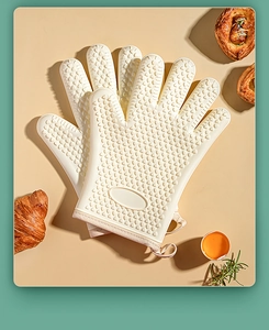 Detail view of non-slip silicone oven glove texture with croissants on a beige background