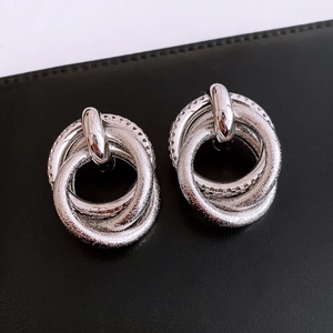 Macro shot of silver knot earrings featuring frosted textures and interlocking rings