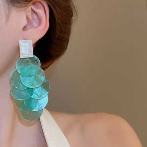Detail of long drop earrings featuring mint green shell discs on model's ear