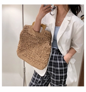 Detail of hand-woven straw tote bag with square wooden handle and beige fabric texture