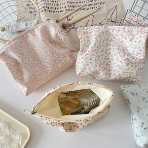 Flat lay of floral canvas makeup bags with cosmetic brushes and beauty accessories