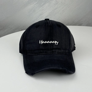Detail of distressed brim and white Haaaaaapy embroidery on black cotton baseball cap